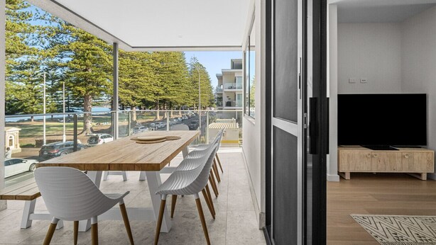 Un appartamento moderno con un balcone, un'area pranzo e un soggiorno con televisore.