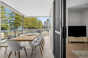Eine moderne Wohnung mit Balkon, Essbereich und Wohnzimmer mit Fernseher.