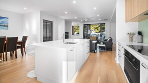 A modern kitchen with white cabinetry, a central island, and a dining area with wooden chairs.