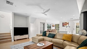 A modern living room with a large L-shaped sofa, a wooden coffee table, and a flat-screen TV.