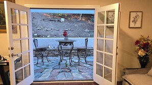 Ein Zimmer mit einer Schiebetür, die auf eine Außenpatio mit einem Steintisch und Stühlen führt.