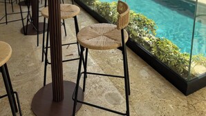 A poolside area with outdoor seating and a view of a modern building. - New Chic 2BR APT. (Punta Cana)