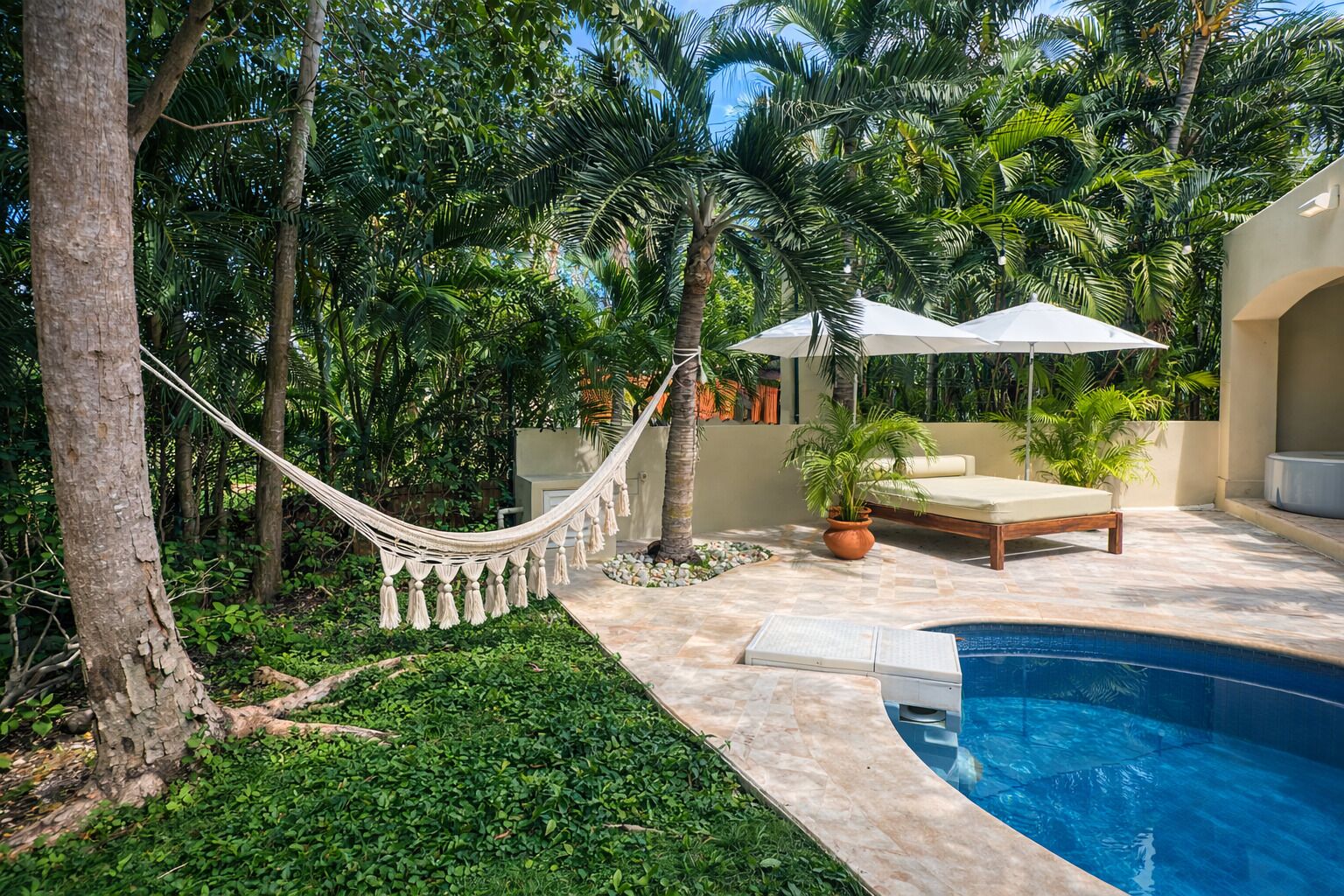 A poolside area with a hammock, lounge chairs, and a small pool.