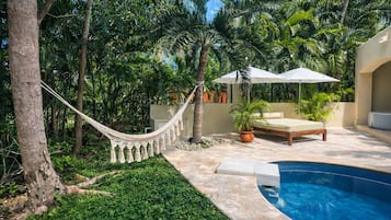 Un espace aménagé au bord de la piscine, avec un hamac, des chaises longues et une petite piscine.