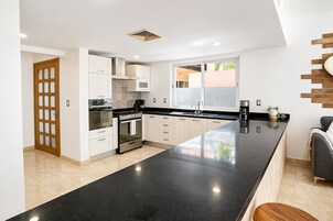 Una cocina moderna con una isla grande, electrodomésticos de acero inoxidable y un ventanal que proporciona luz natural.