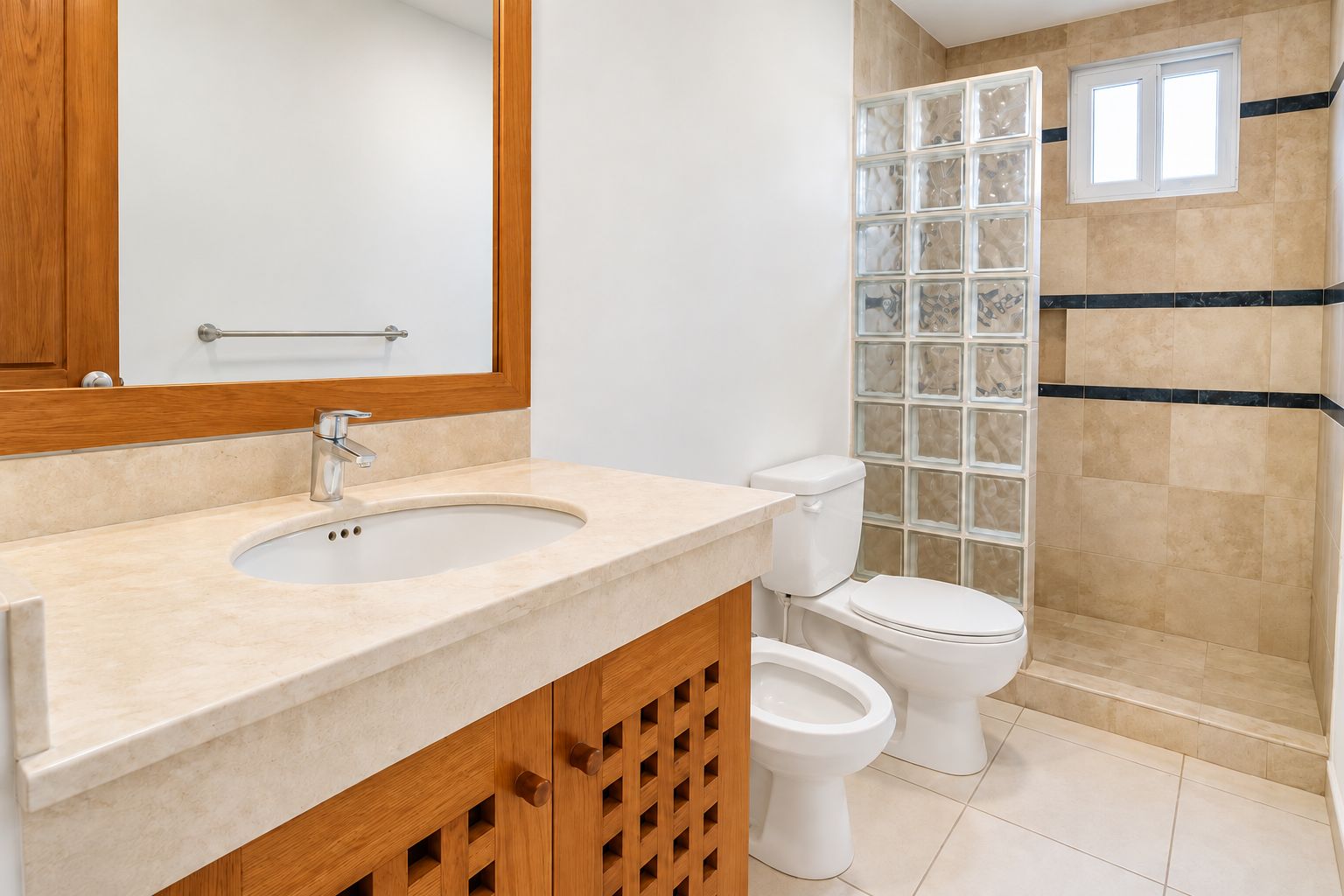 A bathroom with a sink, mirror, toilet, and a shower area.