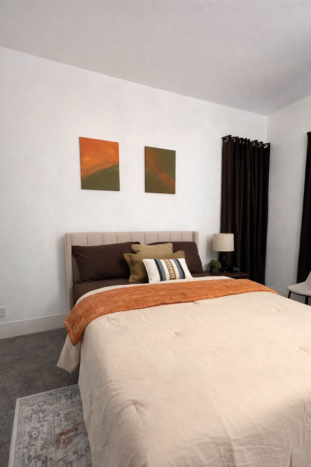 Een hotelkamer met een bed, een nachtkastje, een lamp en twee aan de muur bevestigde schilderijen.