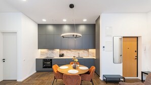A modern kitchen with grey cabinets, a marble backsplash, and a central island with a sink. - Vytauto 43 Residence – Lietūkis by Domvia (Kaunas)