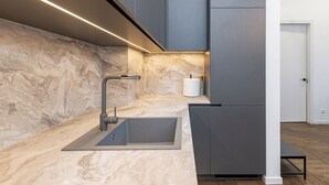 A modern kitchen with a marble countertop, a stainless steel sink, and a sleek faucet. - Vytauto 43 Residence – Lietūkis by Domvia (Kaunas)