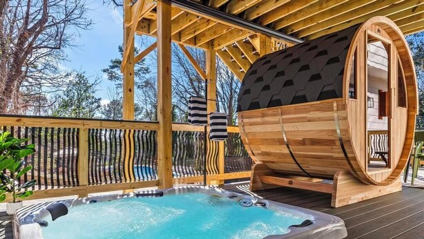 Puinen terassi, jossa on poreallas, sauna ja puinen tynnyri.