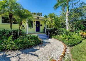 A house with a front porch, a blue door, and a gravel pathway leading to the entrance. - Coastal Canopy, Private Pool: 15 Min to Beach (Bradenton)