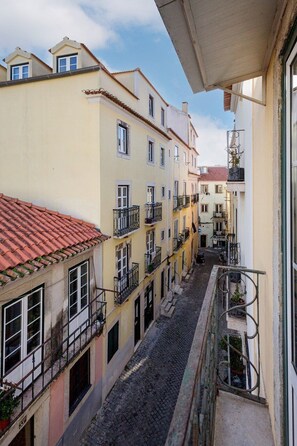 A narrow street with buildings on either side, balconies with railings, and a cobblestone road. - Lisbon Cozy Nest in Santa Catarina (Lisbon)