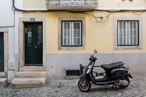 A scooter parked in front of a building with a number 32 sign, a door, and two windows with bars. - Lisbon Cozy Nest in Santa Catarina (Lisbon)