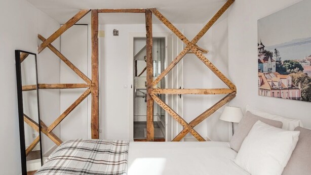 Ein Schlafzimmer mit einem Bett, einem Spiegel, einer Holzbalkendecke, einem Gemälde und einer Lampe.