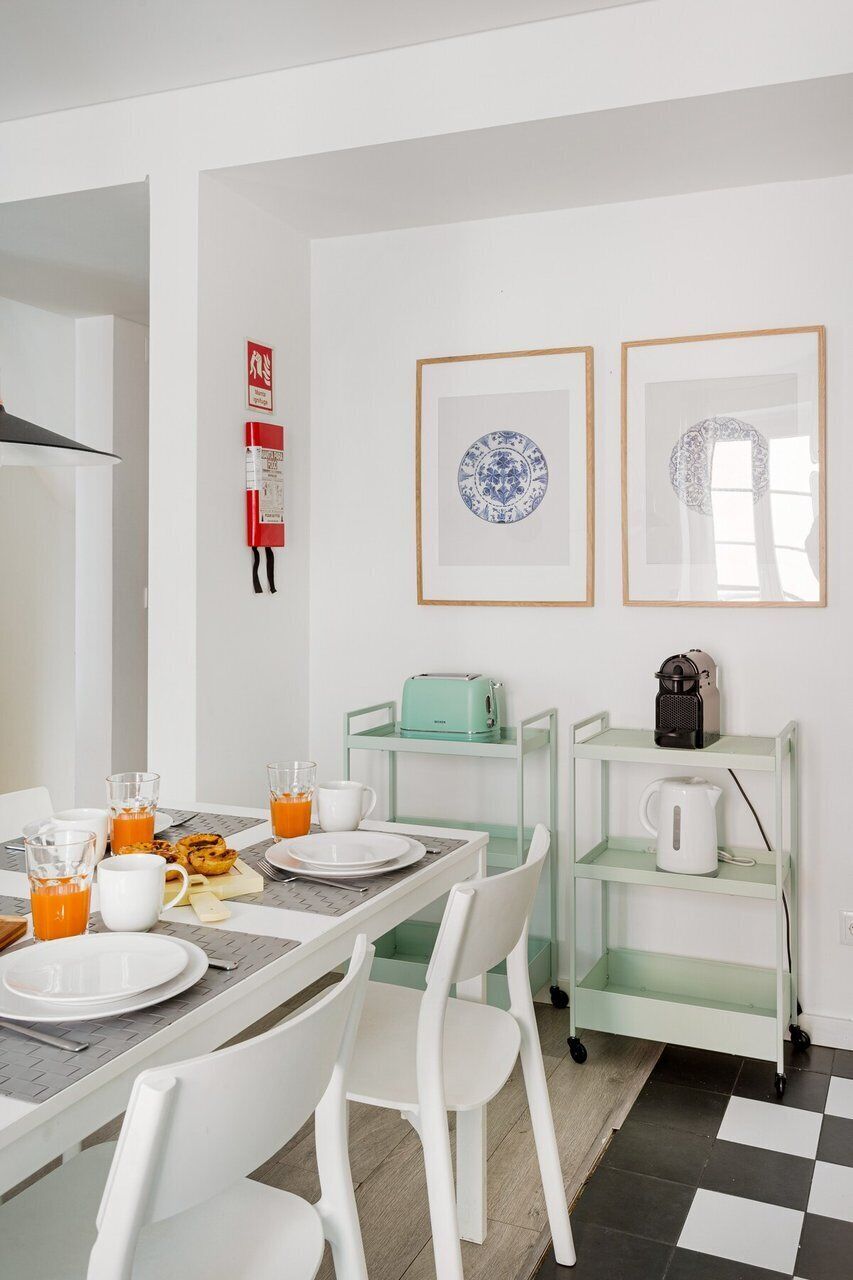A modern kitchen with white cabinets, a dining table with chairs, a coffee maker, and a kettle on a cart.