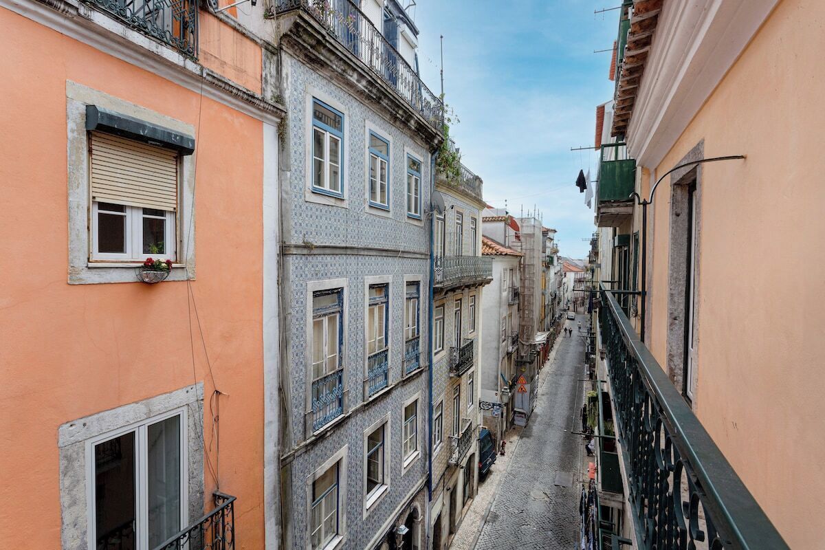 Une rue étroite, bordée de bâtiments des deux côtés, avec des balcons et des fenêtres.