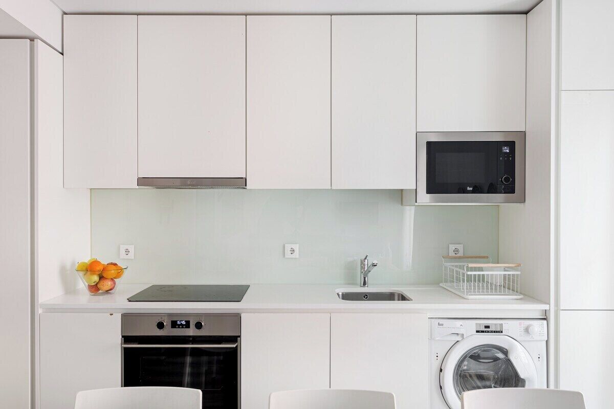 A compact kitchen with a microwave, oven, and washing machine.