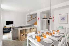 Eine moderne Küche mit Essbereich, weißen Möbeln und einer Treppe.