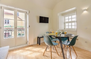 A dining area with a table, chairs, and a TV mounted on the wall. - Design Apartment in Typical Alfama (Lisbon)