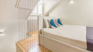 Una camera da letto moderna con un letto, una scala in legno e un lucernario.