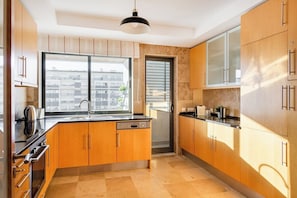 Eine moderne Küche mit Holzausbau, einer schwarzen Arbeitsplatte und einem großen Fenster.