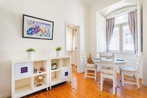 A room with a white cabinet, a framed picture, a window with curtains, and a round table with chairs. - Baixa-Chiado Getaway (Lisbon)