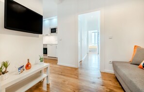 Eine moderne Wohnung mit Wohnzimmer, Küche und einem Flur, der zu einem Balkon führt.