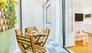 Un coin repas avec une table dressée pour quatre personnes, un cactus et un saladier rempli de fruits et de jus.