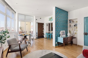 Ein modernes Wohnzimmer mit Essbereich, großen Fenstern und einer blauen Akzentwand.