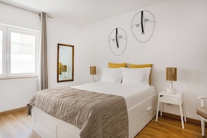 Ein Schlafzimmer mit einem Bett, Nachttischen, einem Spiegel und Wandbildern.