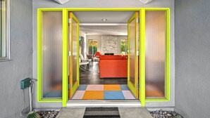 Un interior moderno con un sofá naranja brillante, una pared de acento de piedra y una alfombra colorida.