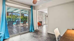 Un interior moderno con un cerramiento de vidrio que da a una zona de piscina, un ventilador de techo y una pared de piedra.