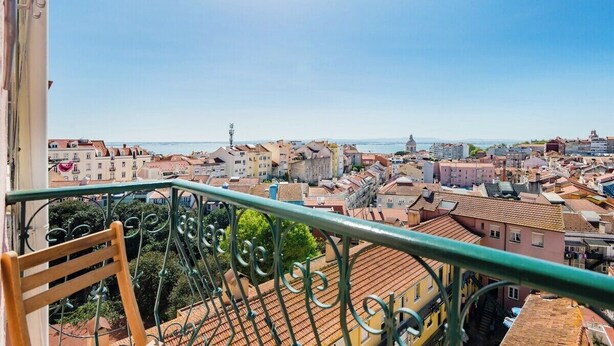 Un balcon offrant une vue sur le paysage urbain, avec des bâtiments et une côte lointaine.