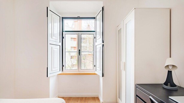 Une pièce avec une grande fenêtre, un lit, un bureau et une armoire.