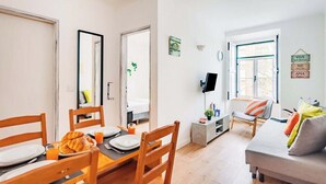 Un salon moderne comprenant un coin repas, un téléviseur et un canapé.