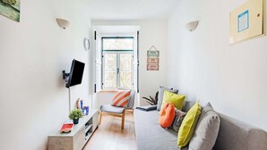 Un salon moderne avec un canapé, un fauteuil, un téléviseur et une fenêtre.