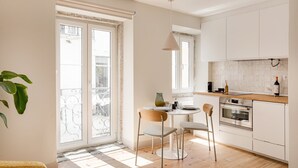 Eine moderne Küche mit weißen Schränken, einer Holzauskładfläche und einem Essbereich mit zwei Stühlen und einem Tisch.