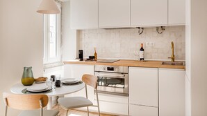 Eine moderne Küche mit weißen Schränken, einer Holz Arbeitsplatte, einem eingebauten Ofen und einem Essbereich mit einem runden Tisch und Stühlen.