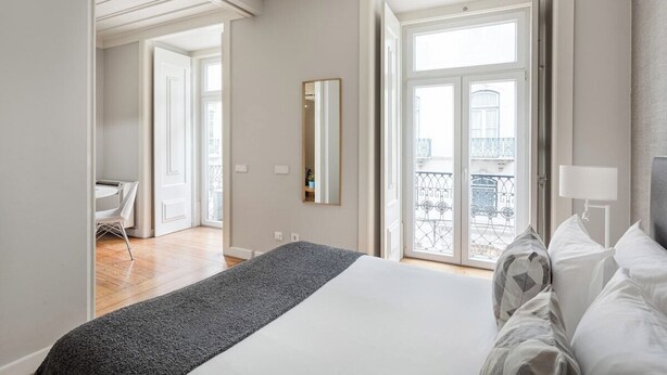 A hotel room with a bed, a mirror, a balcony with a railing, and a door leading to another room. - Trendy Flat in the iconic Chiado (Lisbon)