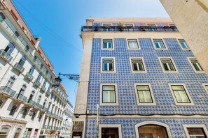 Ein Gebäude mit einer blau-kachelfarbenen Fassade, mehreren Fenstern und Balkonen.