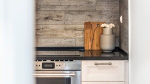Una cocina con salpicadero de madera, estufa y un armario blanco.