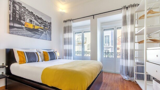 Una habitación de hotel con cama, armario, un cuadro y vistas al exterior.