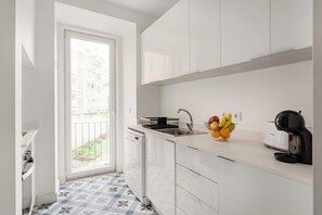 A compact kitchen with white cabinets, a dishwasher, a sink, a toaster, and a fruit bowl. - Lisbon City Vibes, 2BR Flat (Lisbon)