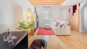 Ein modernes Wohnzimmer mit Holzboden, einem weißen Sofa, einem roten Teppich und einer Pflanze.