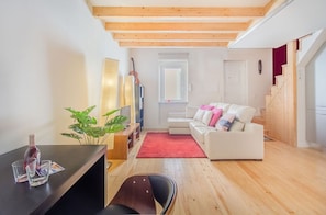 Een moderne woonkamer met een houten plafond, een witte bank, een rode vloerkleed en een plant.