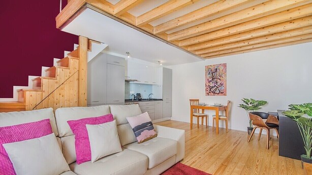Ein modernes Wohnzimmer mit Treppe, Essbereich und Küche.