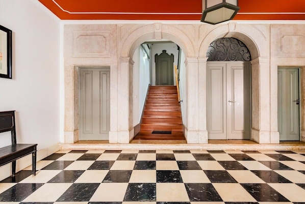 Ein Schachbrettmuster auf dem Boden, eine Treppe und eine Tür mit einem grünen Griff.