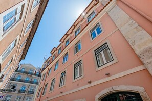 Ein mehrstöckiges Gebäude mit einer rosafarbenen Fassade, zahlreichen Fenstern und Balkonen.
