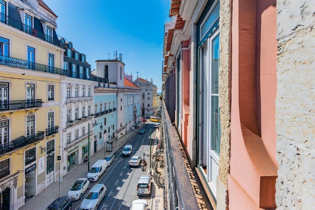 Eine schmale Straße mit Häusern an beiden Seiten, einem klaren blauen Himmel und einigen Autos.