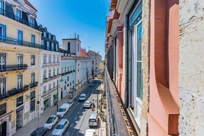 A narrow street with buildings on either side, a clear blue sky, and a few cars on the road. - Chiado Prime Camões Apartment (Lisboa)